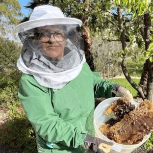 Ayele's mother in bee protective round veil & hat holding harvested honey combs